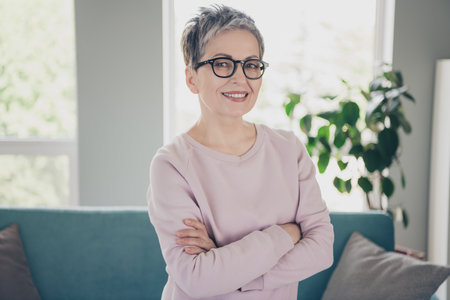Photo of adorable sweet lady wear pink sweatshirt smiling arms crossed indoors room home houseの写真素材
