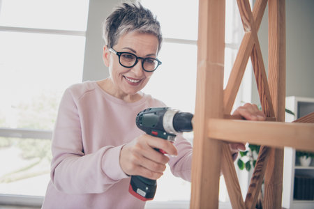 Photo of adorable sweet lady wear pink sweatshirt fixing furniture indoors room home houseの写真素材