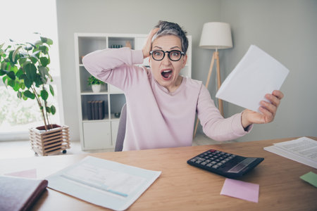 Photo of angry shocked lady wear pink sweatshirt counting calculator indoors room home houseの写真素材