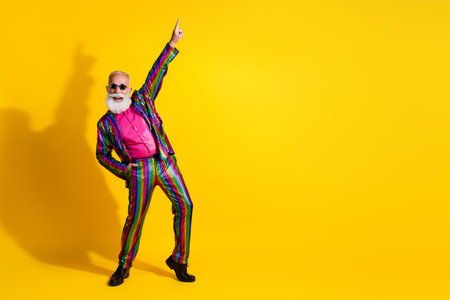 Photo of crazy charismatic man wear stylish striped bright suit dance night club theme party isolated on yellow color backgroundの写真素材