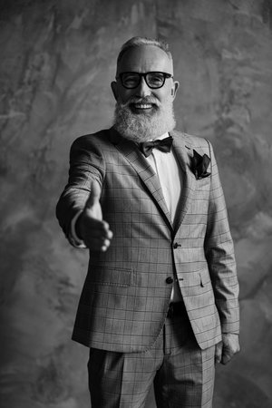 Cooperating people concept. Hello Vertical portrait excited confident freelancer wearing stylish trendy checkered grey classic suit, maroon accessories giving hand to you isolated on gray backgroundの写真素材