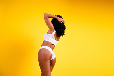 No filter studio photo of fit slender woman underwear enjoying self acceptance blank space isolated yellow color backgroundの写真素材