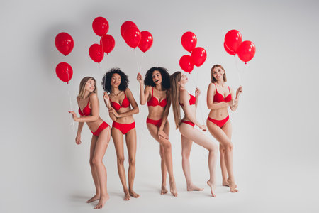 Full body photo of attractive young girls cheerful hold air balloons wear red fashion lingerie isolated white wall background no filterの写真素材