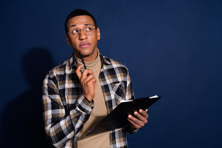 Photo of doubtful unsure guy dressed plaid shirt signing contract looking emtpy space isolated blue color backgroundの写真素材