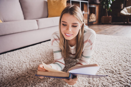 Young woman relaxing at home with a book in a cozy living roomの写真素材