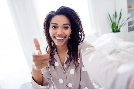 Young woman in polka dot pajamas enjoying a fresh morning indoors, projecting a joyful and relaxed atmosphereの写真素材