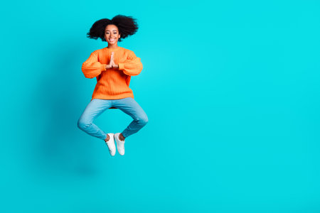 Full length photo of lovely young lady meditate jumping dressed stylish knitted orange garment...