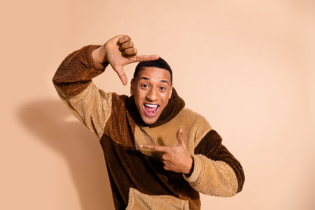 Photo of cheerful positive man wear trendy clothes have fun enjoy hobby isolated on beige color backgroundの写真素材