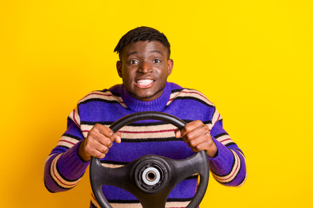 Photo of nice young man arms hold wheel wear pullover isolated on yellow color backgroundの写真素材