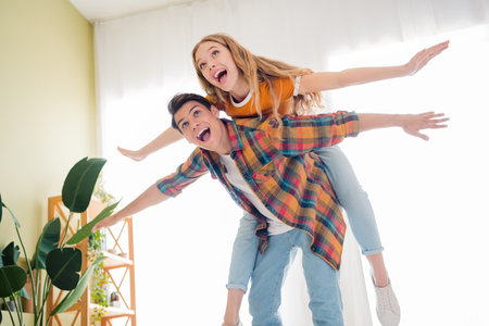 Joyful young couple bonding indoors on a cheerful day, enjoying weekend in casual style, celebrating friendship and love togetherの写真素材