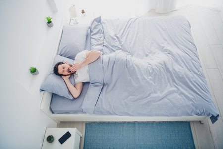Top view photo of funky mature guy sleepwear pajama lying bed yawning indoors home house bedroom
