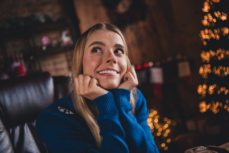 Photo of lovely young woman look dreamy empty space dressed christmas outfit day light home party decoration interior roomの写真素材
