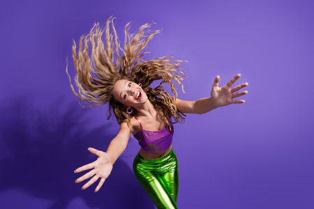 Photo of pretty young girl flying hair arms welcome you wear shiny top isolated on violet color backgroundの写真素材