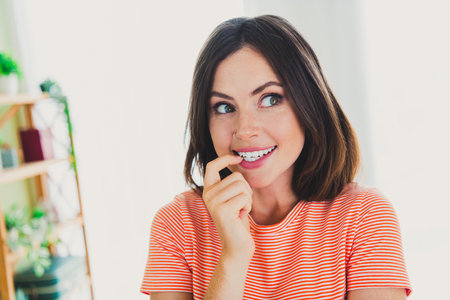 Charming young woman in a striped t-shirt enjoying a leisure day indoors in a stylish living room