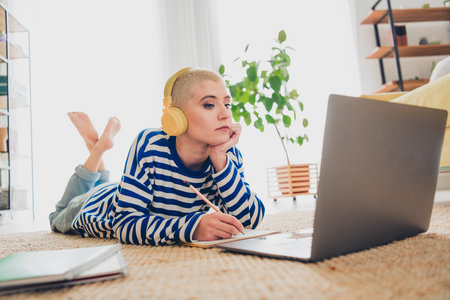 Young woman enjoying a relaxing day at home with music and online content in a cozy living room...