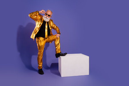 Full size photo of old macho man step white cube cool posing wear glamour stylish golden outfit party isolated on purple color backgroundの写真素材