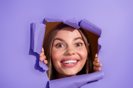 Photo portrait of attractive young woman peek cheerful excited face tear purple paper color...