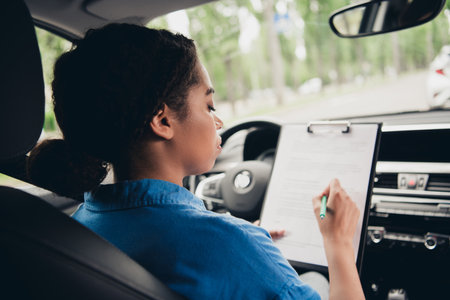 Young woman in a car taking driving notes during a sunny day in the city street