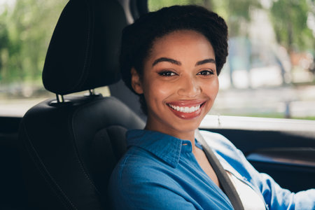 Happy young woman driving a car on a sunny day in the city, enjoying the freedom and adventure of...