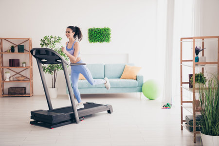 Young woman enjoying treadmill workout in bright modern apartment with stylish decor and natural lightの写真素材