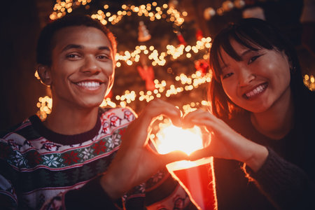 Photo of happy young couple show heart symbol dressed christmas garment tradition atmosphere decor house indoors roomの写真素材