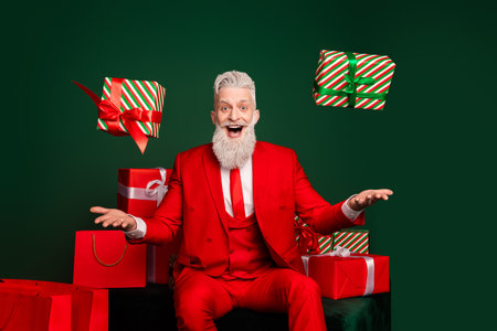 Portrait of classy trendy santa catch throw giftbox wear red new year x-mas suit isolated on green color backgroundの写真素材