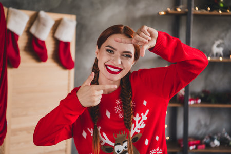 Portrait of nice young woman show cadre gesture toothy smile wear sweater new year x-mas time flat indoorsの写真素材