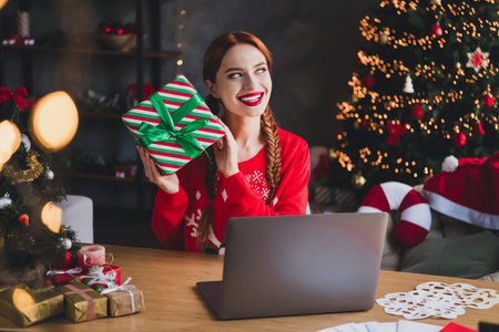 Photo of pretty young girl laptop table hold giftbox think wear red christmas festive sweater...