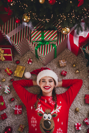 Above view portrait of nice young woman lay floor hands behind head wear sweater new year xmas time flat indoorsの写真素材