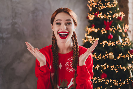 Photo of pretty young girl open mouth raise hands wear sweater christmas festive holiday time apartment indoorsの写真素材