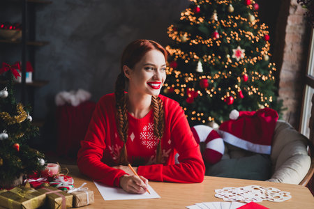 Photo of pretty young girl write letter contemplate wear sweater christmas festive holiday time apartment indoorsの写真素材