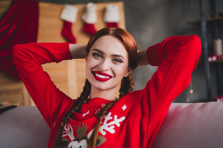 Photo of pretty young girl sit couch hands behind head wear sweater christmas festive holiday time apartment indoorsの写真素材