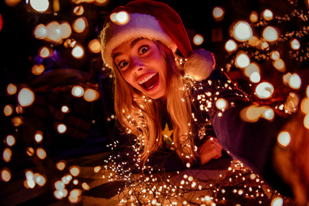 Photo of young woman lying floor excited take selfie photo dressed christmas outfit tradition garland lights atmosphere house indoors roomの写真素材