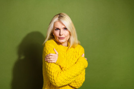Photo of lovely charming lady wear trendy yellow sweater hug herself cold weather isolated on green color backgroundの写真素材