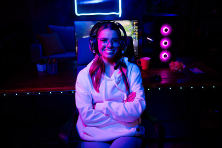 Photo of gamer lovely blonde young lady crossed hands confident play strategy game late night room indoors purple blue neon lightの写真素材