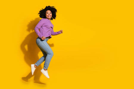 Full size photo of nice young woman jump run empty space isolated on yellow color backgroundの写真素材
