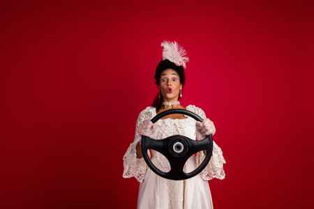 Creative blend of a woman in baroque attire clutching a steering wheel against a vibrant red...