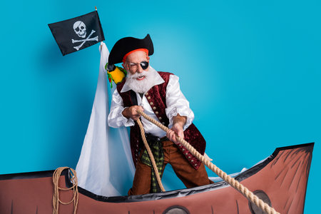 Photo of elderly man pirate costume swimming traveling dangerous adventure isolated on blue color backgroundの写真素材
