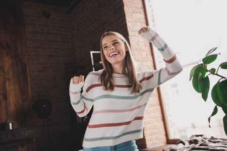 Young woman enjoying a joyful moment indoors, showcasing casual style and natural beauty in a relaxing home environmentの写真素材