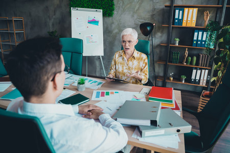 Full length photo of lovely pensioner lady angry boss scolding employee dressed yellow print shirt formalwear startup office room interiorの写真素材