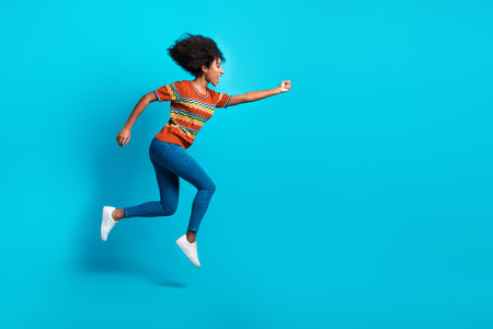 Photo of crazy energetic jumping young funky girl curly hair running for opportunities in life fist up isolated on blue color backgroundの写真素材