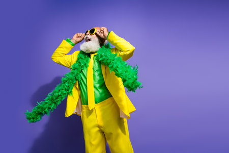 Portrait of funny extravagant aged man empty space advert yellow suit isolated on purple color backgroundの写真素材