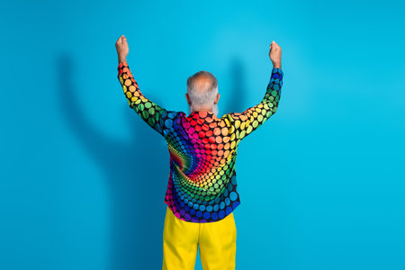 Rear photo of eccentric funky aged man hands hold empty space placard wear shirt isolated on blue color backgroundの写真素材