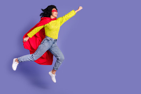 Full length photo of lovely young lady jump flying superhero dressed stylish yellow garment isolated on violet color backgroundの写真素材