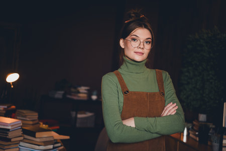 Charming young woman in green turtleneck with brown jumper poses confidently in cozy indoor setting,...