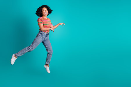 Full size photo of pretty young girl jump look empty space isolated on teal color backgroundの写真素材
