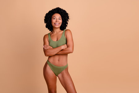 No filter studio photo of slender pretty woman underwear arms crossed enjoying self acceptance isolated beige color backgroundの写真素材