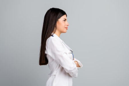 Young female doctor in white uniform looking professional in a hospital setting with a grey backgroundの写真素材