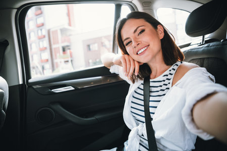 Young woman smiling in car, enjoying a joyful urban rideの写真素材