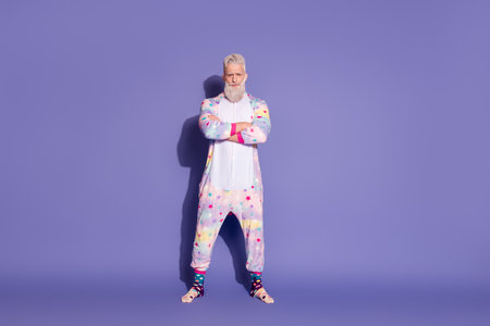 Stylish man in unicorn pajamas stands confidently against a purple backgroundの写真素材